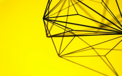 Creative geometric structure casting intricate shadows on a vibrant yellow background.